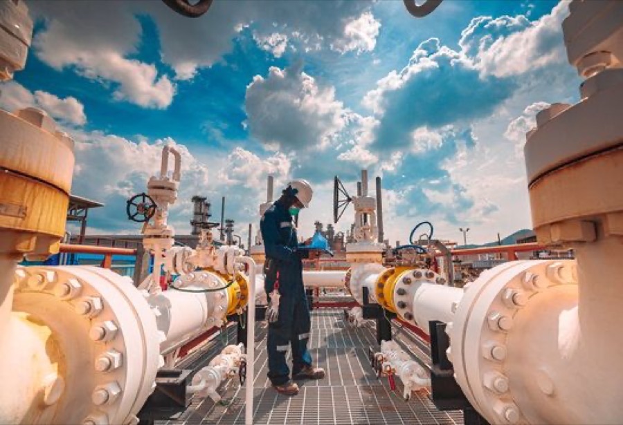 Field operator on an elevated platform among facility piping